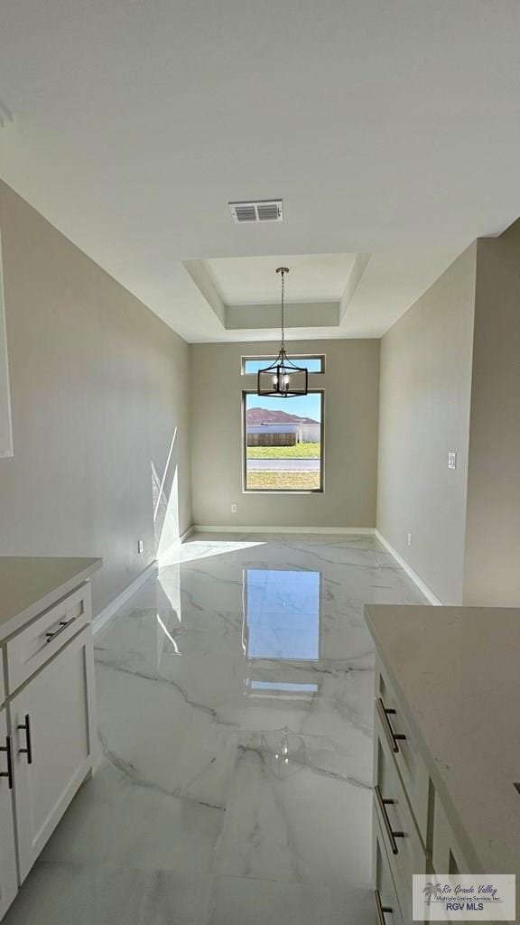 interior space with baseboards, visible vents, a raised ceiling, marble finish floor, and a chandelier