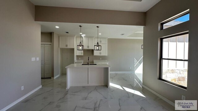 kitchen with pendant lighting, a center island, sink, and light brown cabinets