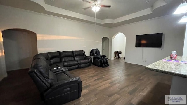 living room with dark hardwood / wood-style floors, ceiling fan, and a tray ceiling