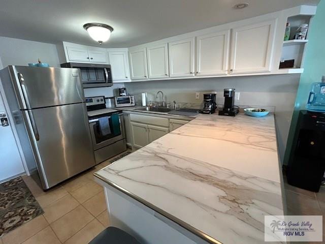 kitchen featuring sink, light tile patterned floors, appliances with stainless steel finishes, light stone counters, and white cabinets