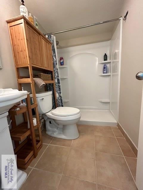 bathroom featuring toilet, tile patterned floors, and a shower with curtain