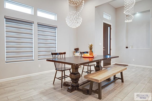 dining space with baseboards, a high ceiling, wood tiled floor, and an inviting chandelier