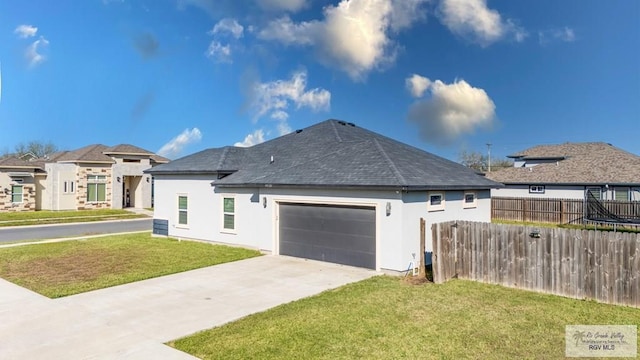 exterior space with a garage, fence, a yard, concrete driveway, and stucco siding