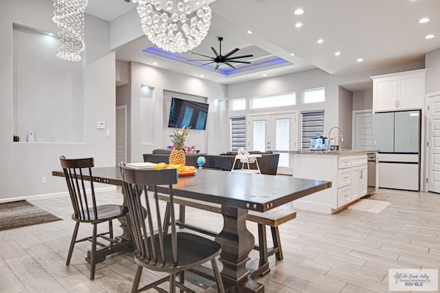 dining space featuring recessed lighting, light wood-style flooring, ceiling fan with notable chandelier, and french doors