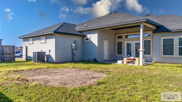 rear view of house with a yard, roof with shingles, cooling unit, and stucco siding