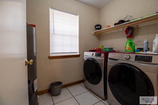 laundry area featuring light tile patterned floors, water heater, washer and dryer, laundry area, and baseboards