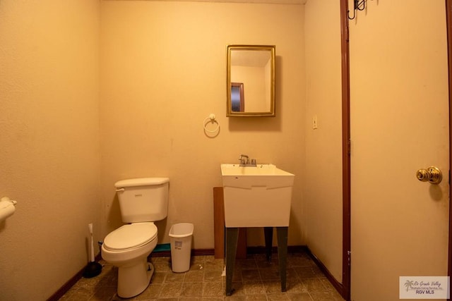 half bathroom featuring baseboards, vanity, and toilet