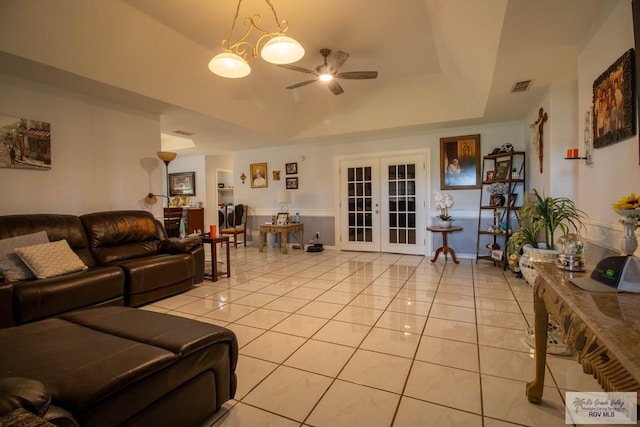 living room featuring light tile patterned floors, ceiling fan, a tray ceiling, and french doors