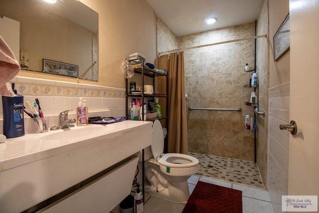 bathroom with tile patterned flooring, toilet, vanity, tile walls, and tiled shower