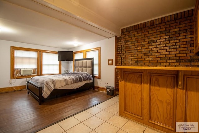 bedroom with light tile patterned flooring, cooling unit, brick wall, baseboards, and beamed ceiling