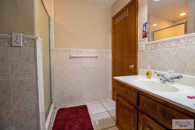 bathroom with a stall shower, tile walls, vanity, and tile patterned floors