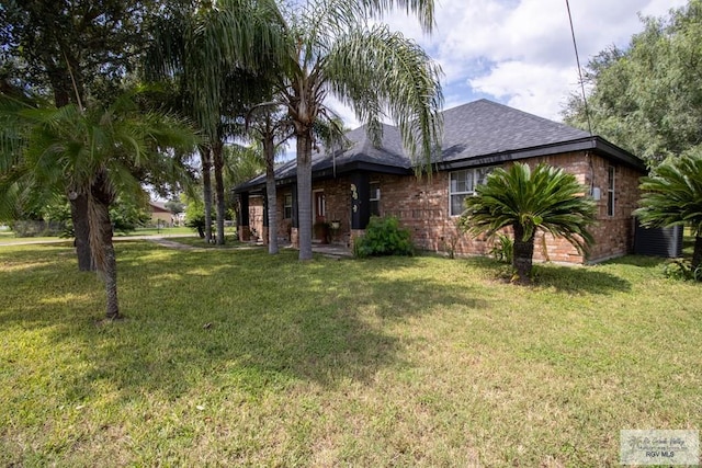 view of front of home featuring brick siding, a shingled roof, and a front yard