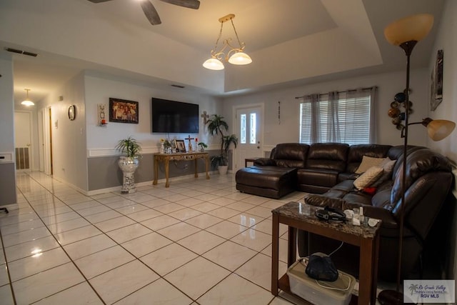 living area featuring light tile patterned floors, visible vents, and a tray ceiling