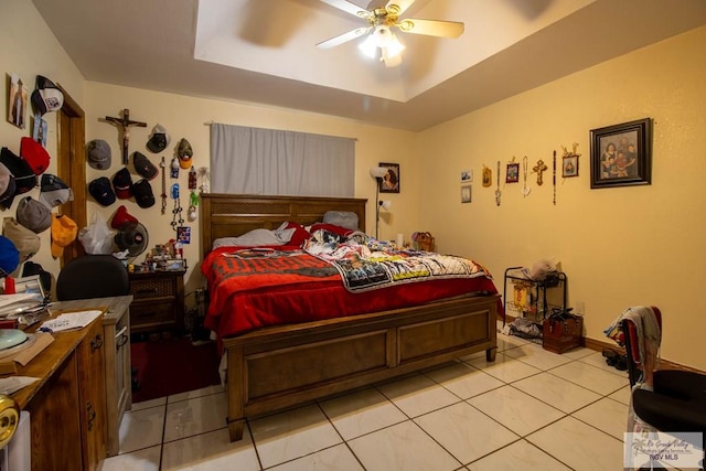 bedroom with light tile patterned floors, ceiling fan, and a tray ceiling