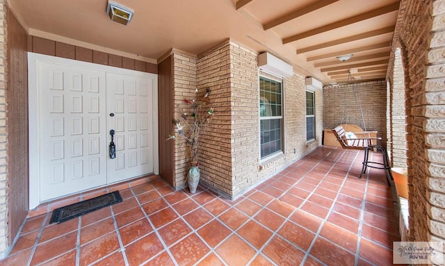 entrance to property with covered porch, brick siding, and visible vents