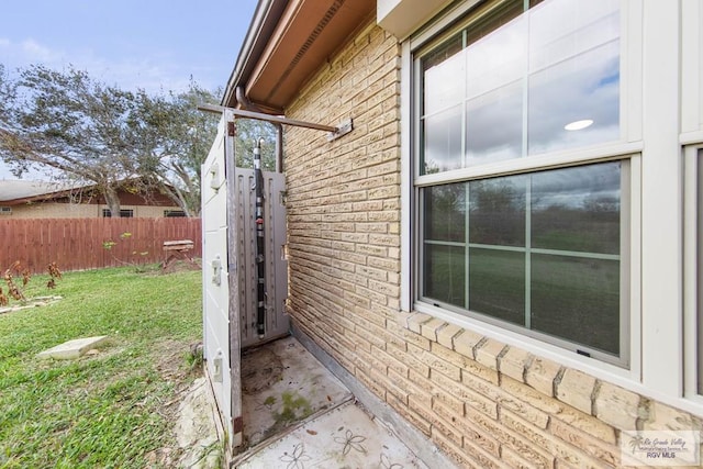 view of side of property with a yard, fence, and brick siding