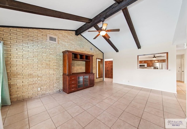 unfurnished living room featuring light tile patterned floors, ceiling fan, beamed ceiling, and brick wall