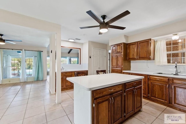 kitchen with light tile patterned floors, light countertops, decorative backsplash, a healthy amount of sunlight, and a sink