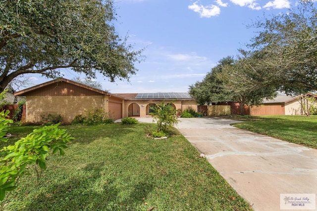 single story home with a front lawn, fence, concrete driveway, roof mounted solar panels, and a garage