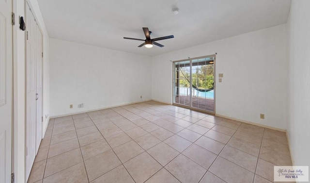 spare room with a ceiling fan, light tile patterned flooring, and baseboards