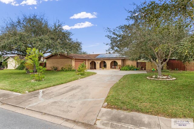 view of front of home with solar panels and a front yard