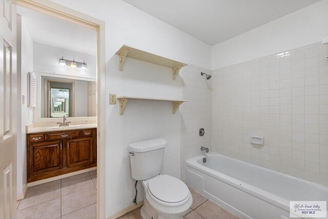 bathroom with toilet, bathing tub / shower combination, baseboards, vanity, and tile patterned floors