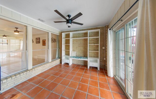 interior space featuring vaulted ceiling with beams, ceiling fan, light tile patterned floors, and brick wall