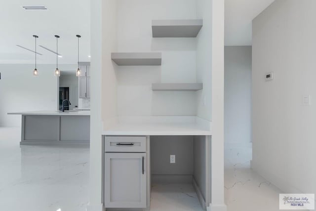 kitchen featuring kitchen peninsula, decorative light fixtures, gray cabinets, and sink