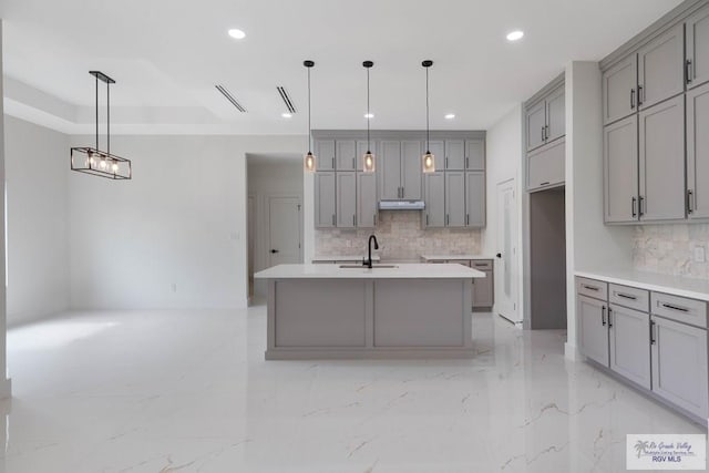 kitchen with gray cabinets, a kitchen island with sink, and pendant lighting