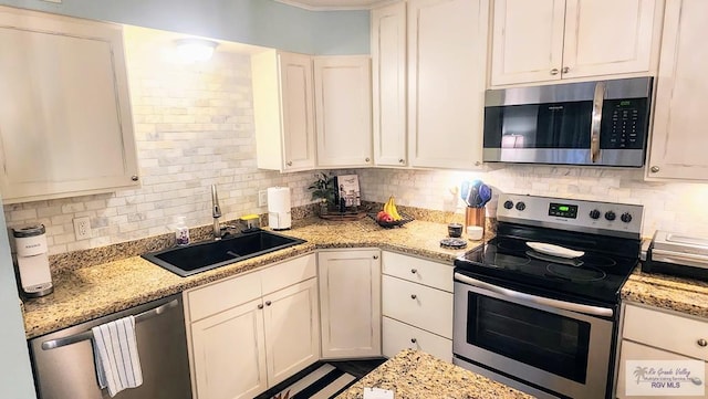 kitchen featuring white cabinets, decorative backsplash, stainless steel appliances, and a sink