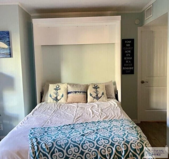 bedroom featuring wood finished floors, visible vents, and crown molding