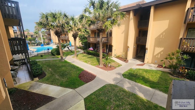 view of property's community with a swimming pool, stairway, and a yard