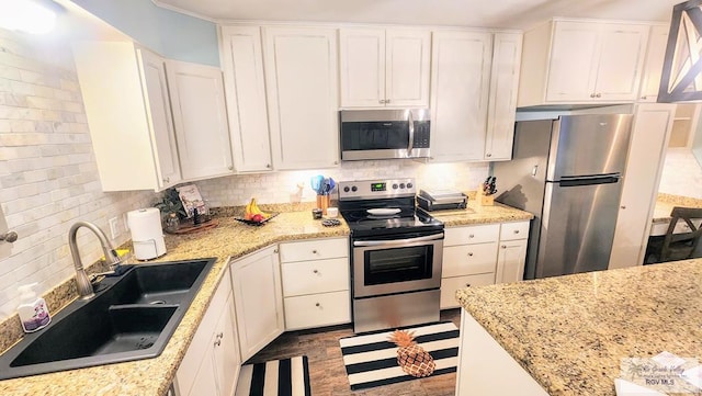 kitchen with white cabinets, decorative backsplash, stainless steel appliances, and a sink