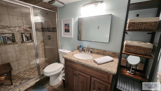 full bathroom featuring a shower stall, toilet, and vanity