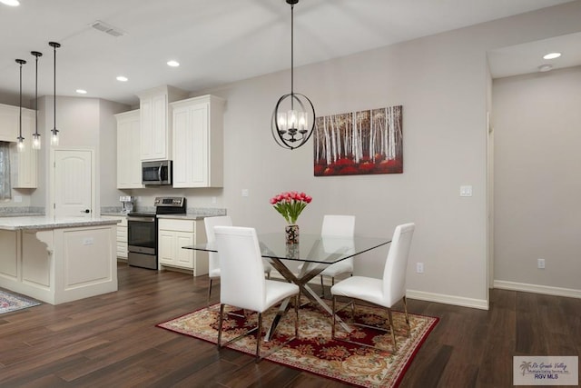 dining room with dark hardwood / wood-style flooring and an inviting chandelier