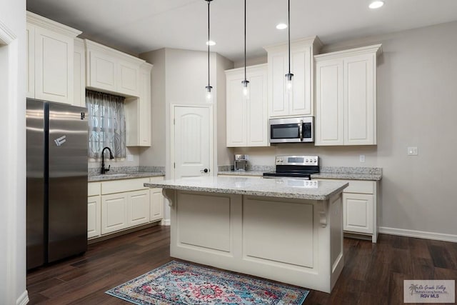 kitchen featuring appliances with stainless steel finishes, decorative light fixtures, a kitchen island, dark hardwood / wood-style flooring, and white cabinetry