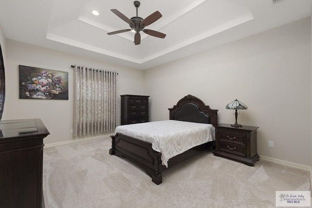 bedroom with ceiling fan, a raised ceiling, and light carpet