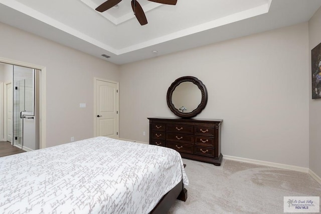 carpeted bedroom featuring ceiling fan, a raised ceiling, and a closet