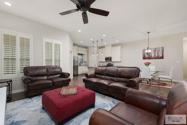 living room with ceiling fan with notable chandelier and light wood-type flooring