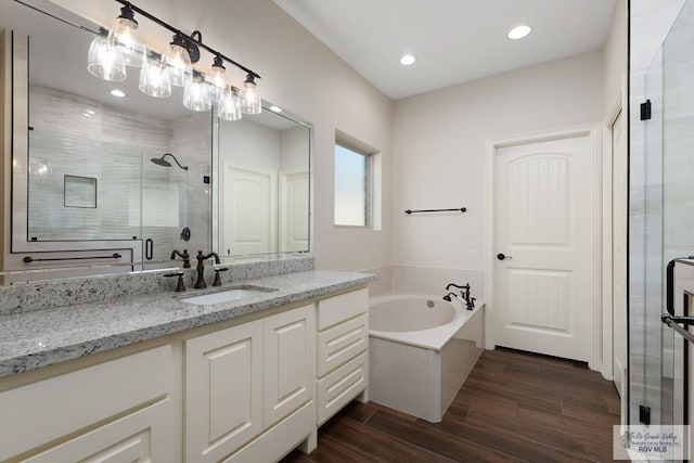 bathroom featuring plus walk in shower, vanity, and hardwood / wood-style flooring