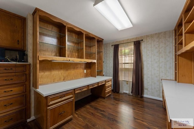 home office with dark wood-type flooring and built in desk