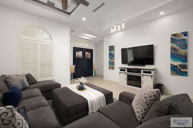 living area featuring a glass covered fireplace, visible vents, and recessed lighting