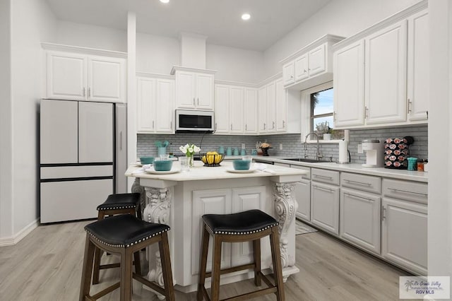 kitchen featuring a breakfast bar, a sink, freestanding refrigerator, and decorative backsplash