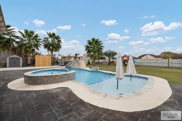 view of swimming pool featuring a lawn, an outbuilding, a storage unit, a water slide, and a pool with connected hot tub