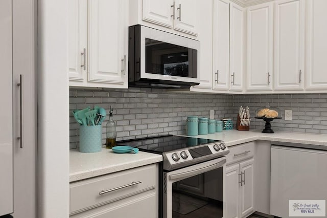 kitchen with white microwave, stainless steel electric range, white cabinetry, and decorative backsplash