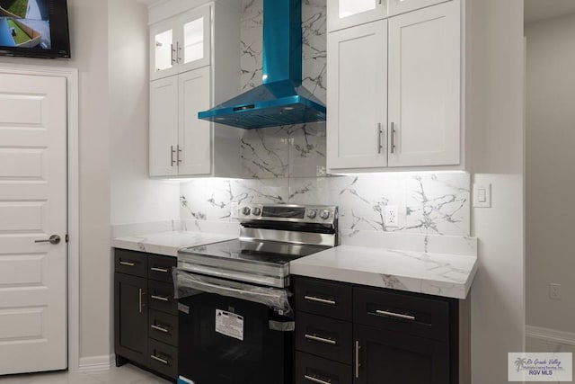 kitchen featuring white cabinetry, stainless steel electric stove, decorative backsplash, and wall chimney range hood