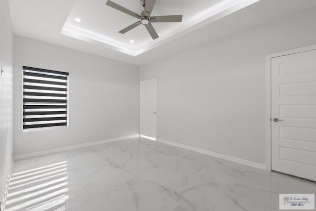 empty room with a raised ceiling and ceiling fan