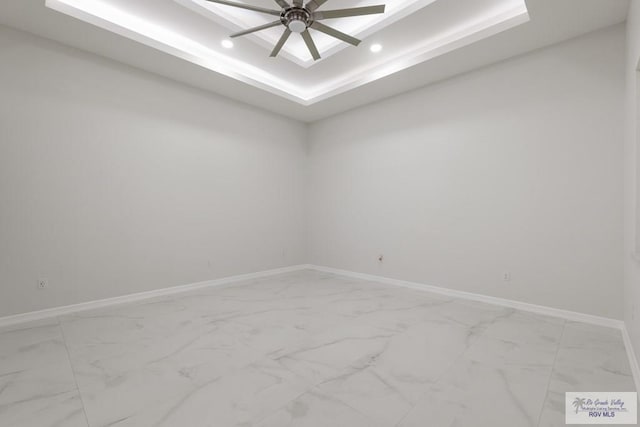 unfurnished room featuring a raised ceiling and ceiling fan