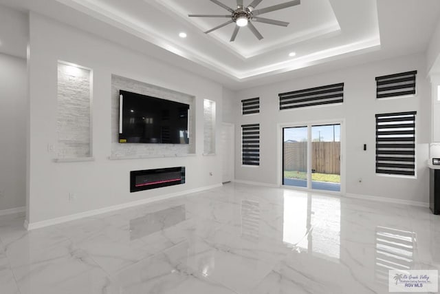 unfurnished living room with a raised ceiling and ceiling fan