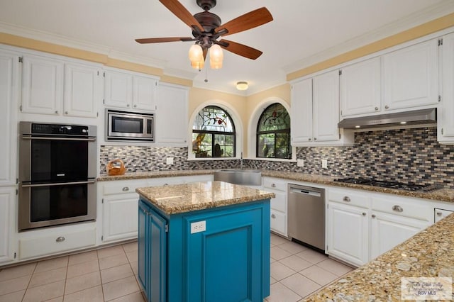 1808 E Palm Valley Dr, Harlingen, TX 78552 - kitchen featuring stainless steel appliances, under cabinet range hood, light tile patterned flooring, white cabinets, and ornamental molding